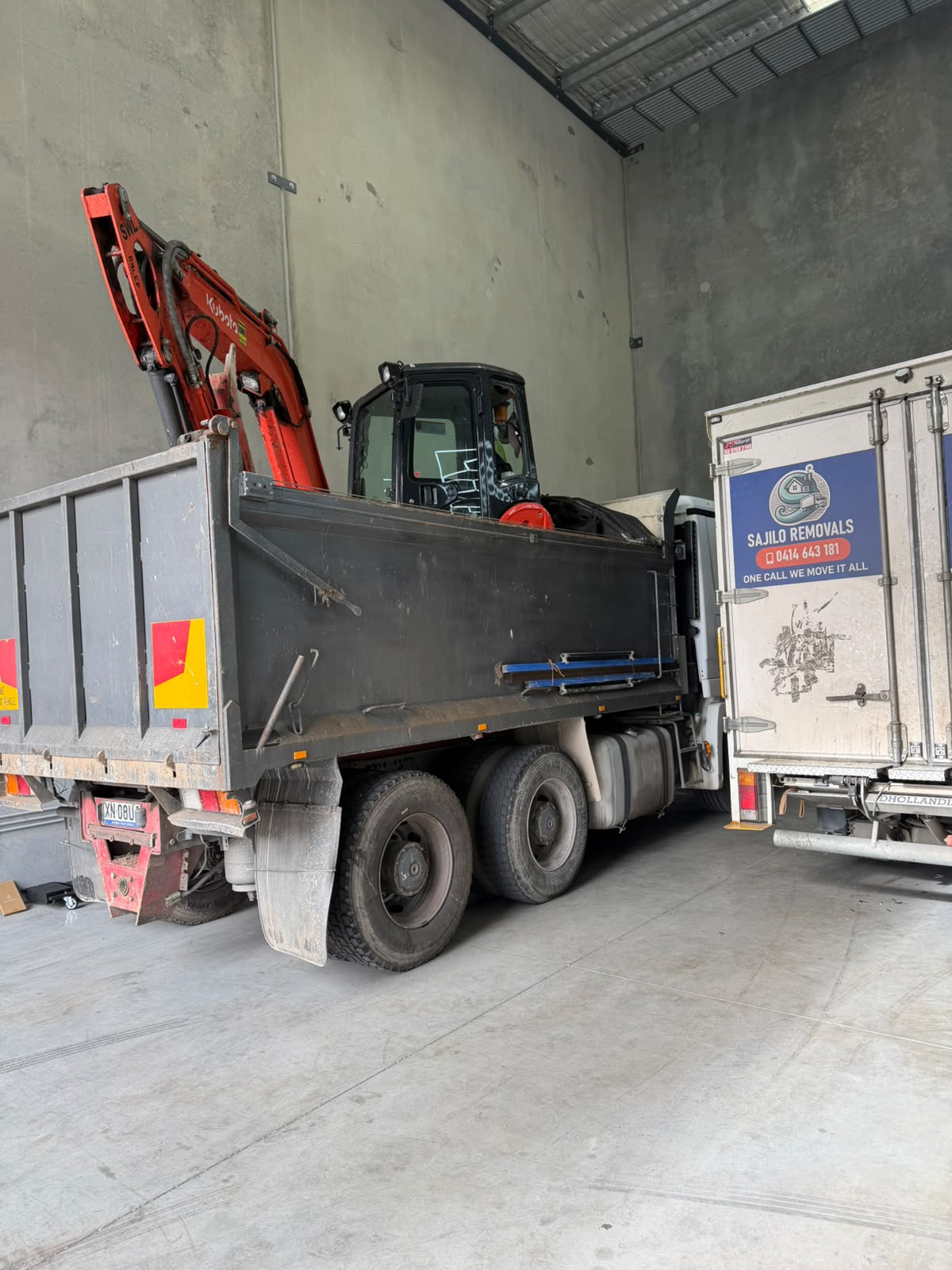 Tipper truck loaded with an excavator inside the workshop